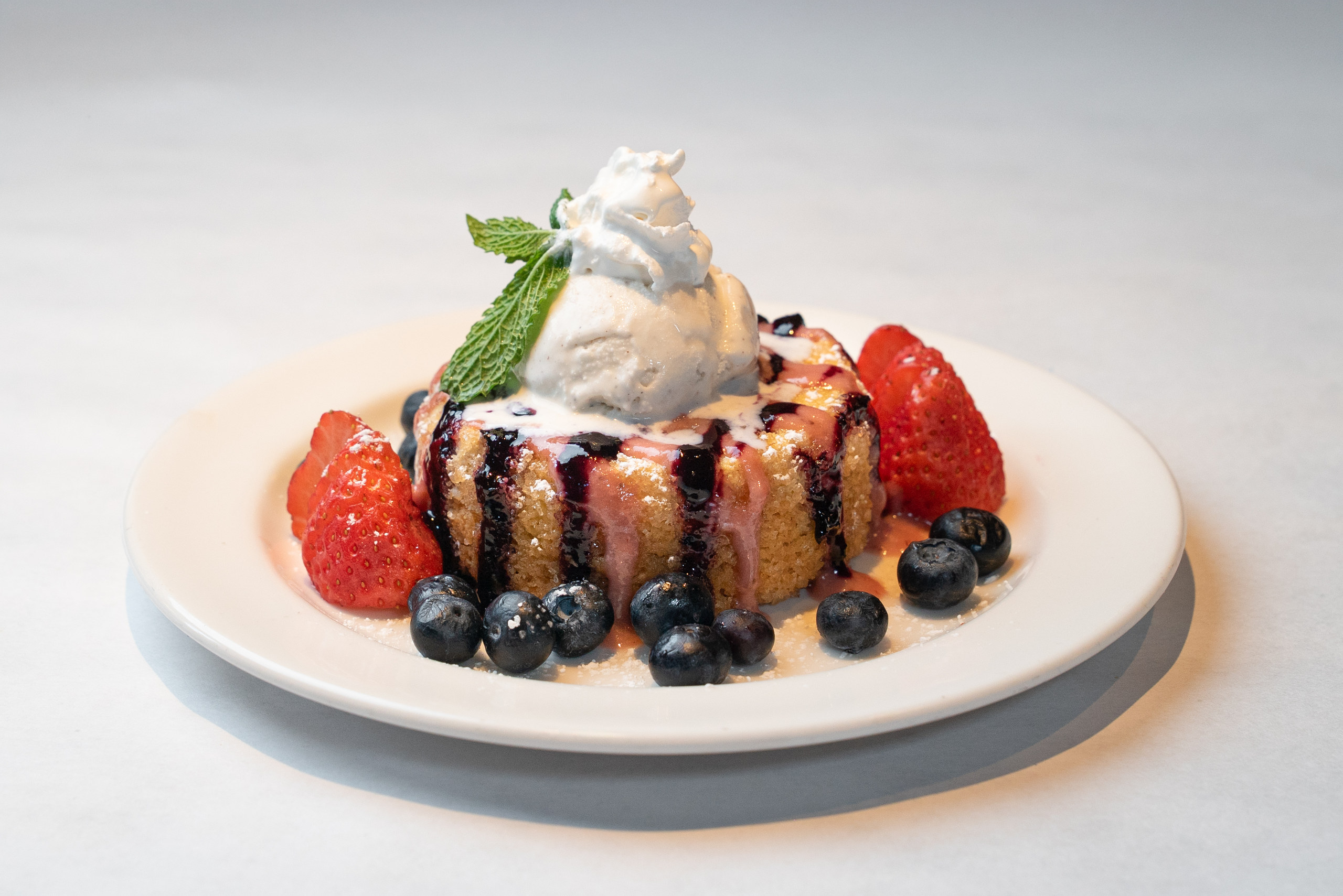 Butter cake with berries, berry drizzle and vanilla ice cream — Denver restaurant food photography