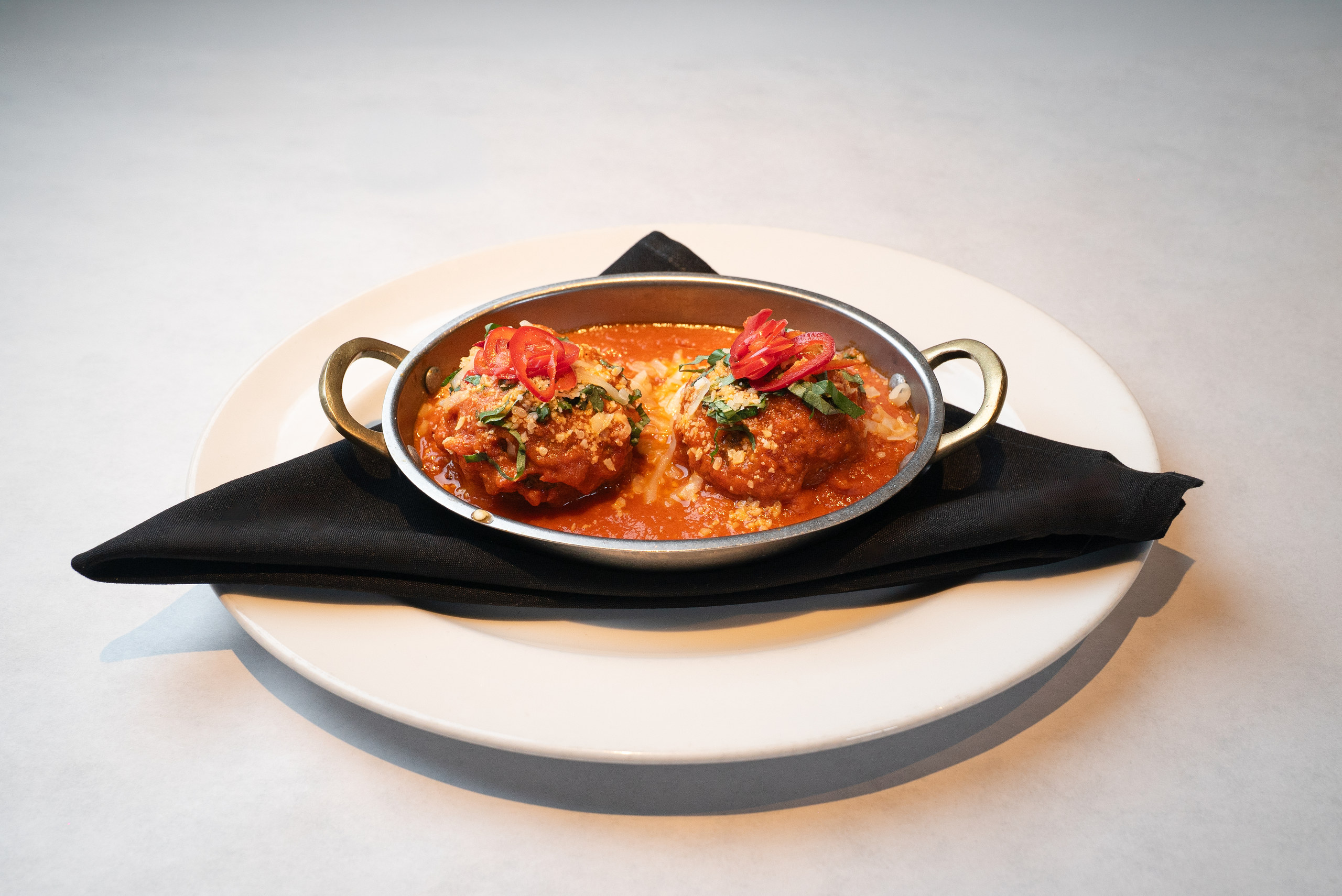 Meatballs in marinara with fresh chili and basil in a copper dish — Denver restaurant food photography