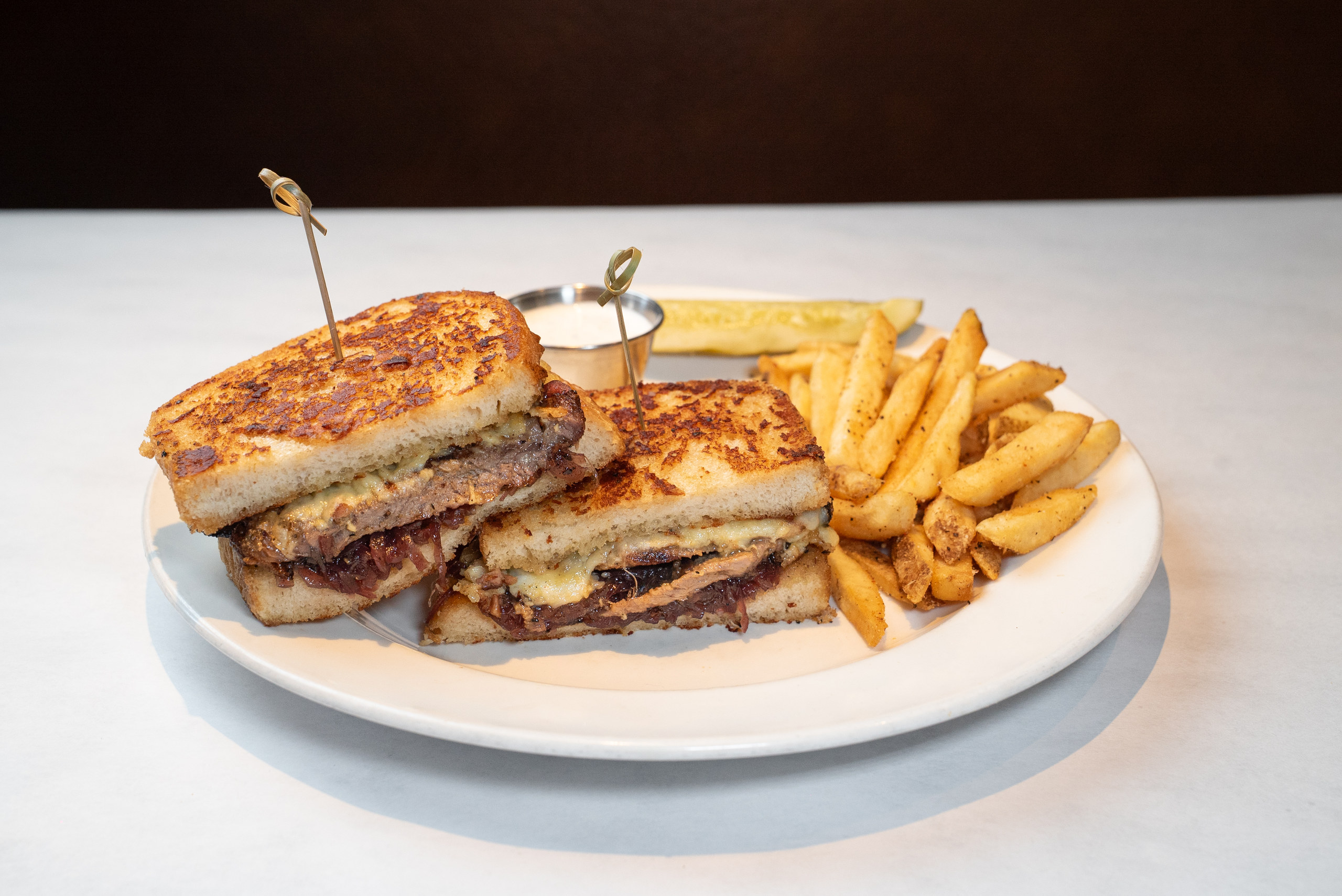 Ribeye steak sandwich with caramelized onions and fries — Denver restaurant food photography